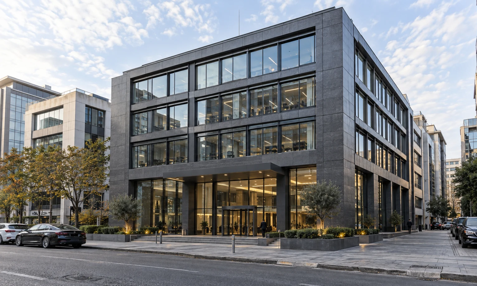 Cam ve taş cepheli, giriş alanı düzenlenmiş modern ofis binası.